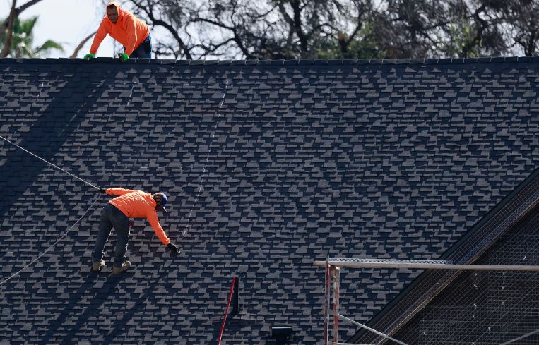Construction workers rebuild a home in Altadena, Calif.
