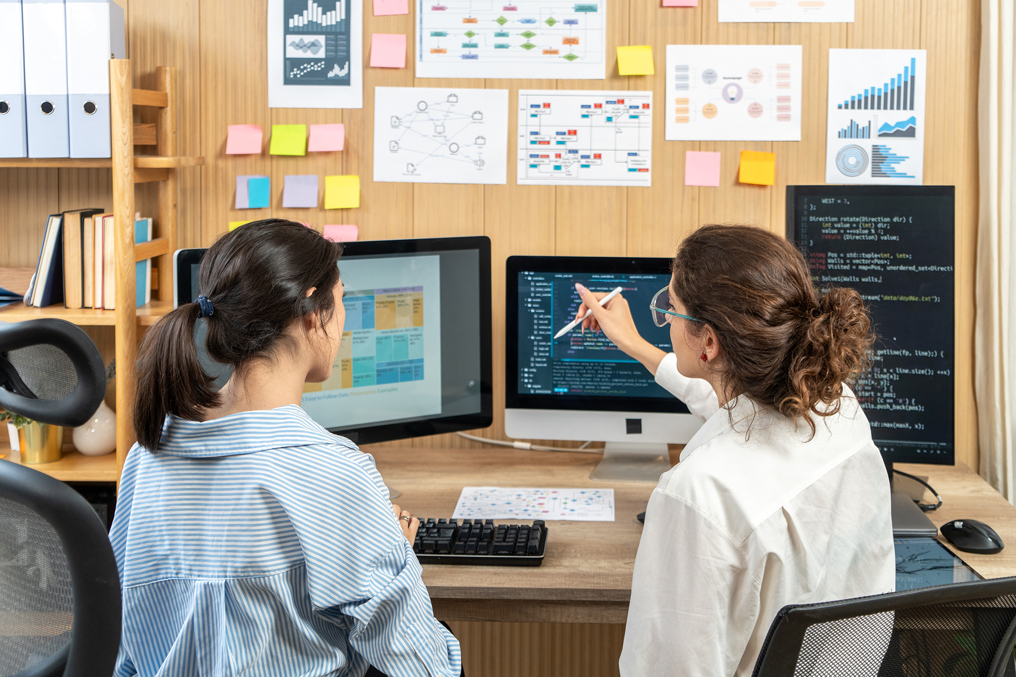Two employees going over data on computer screens.