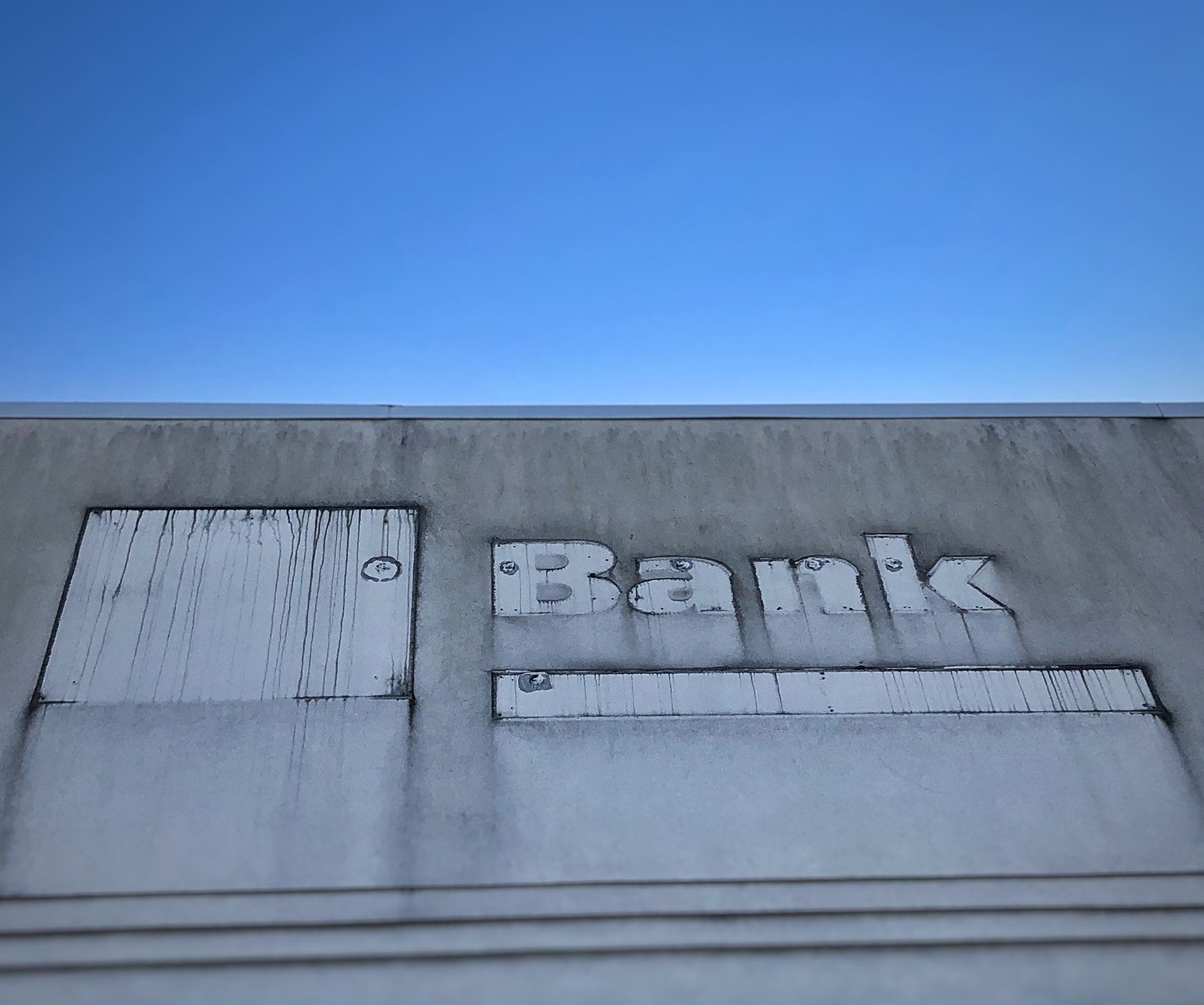 The outline of a "bank" sign on the facade of a building.