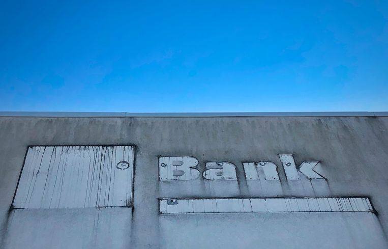 The outline of a "bank" sign on the facade of a building.
