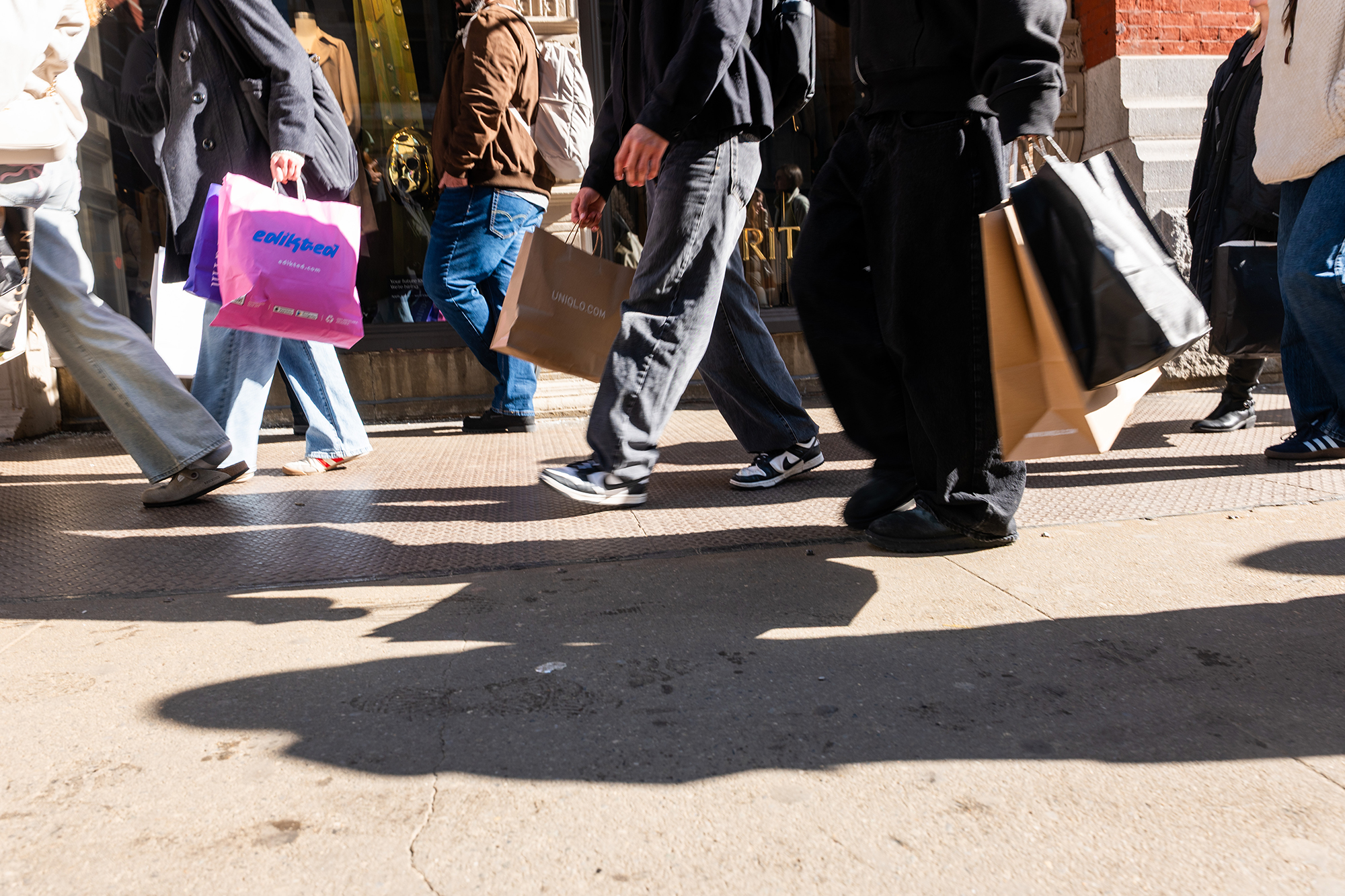 People walk with shopping bags.
