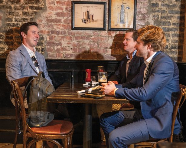 John Lewis, Vice President of Investments at North Bridge has drinks at a nearby pub, MJ Smith's on 45th and Madison, after work to with Eric Conway, Senior Director of Hotel Franchise Finance at Western Alliance, center, and Conor Barry, Vice President at Aareal Bank on June 15, 2026 in Manhattan, New York.