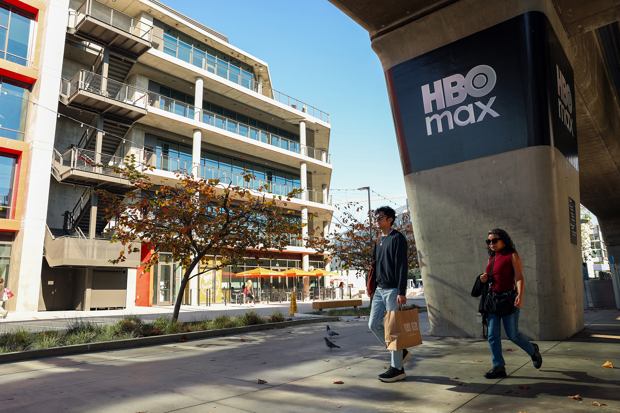 Pedestrians pass an HBO Max logo under a metro rail station in Culver City, Calif.