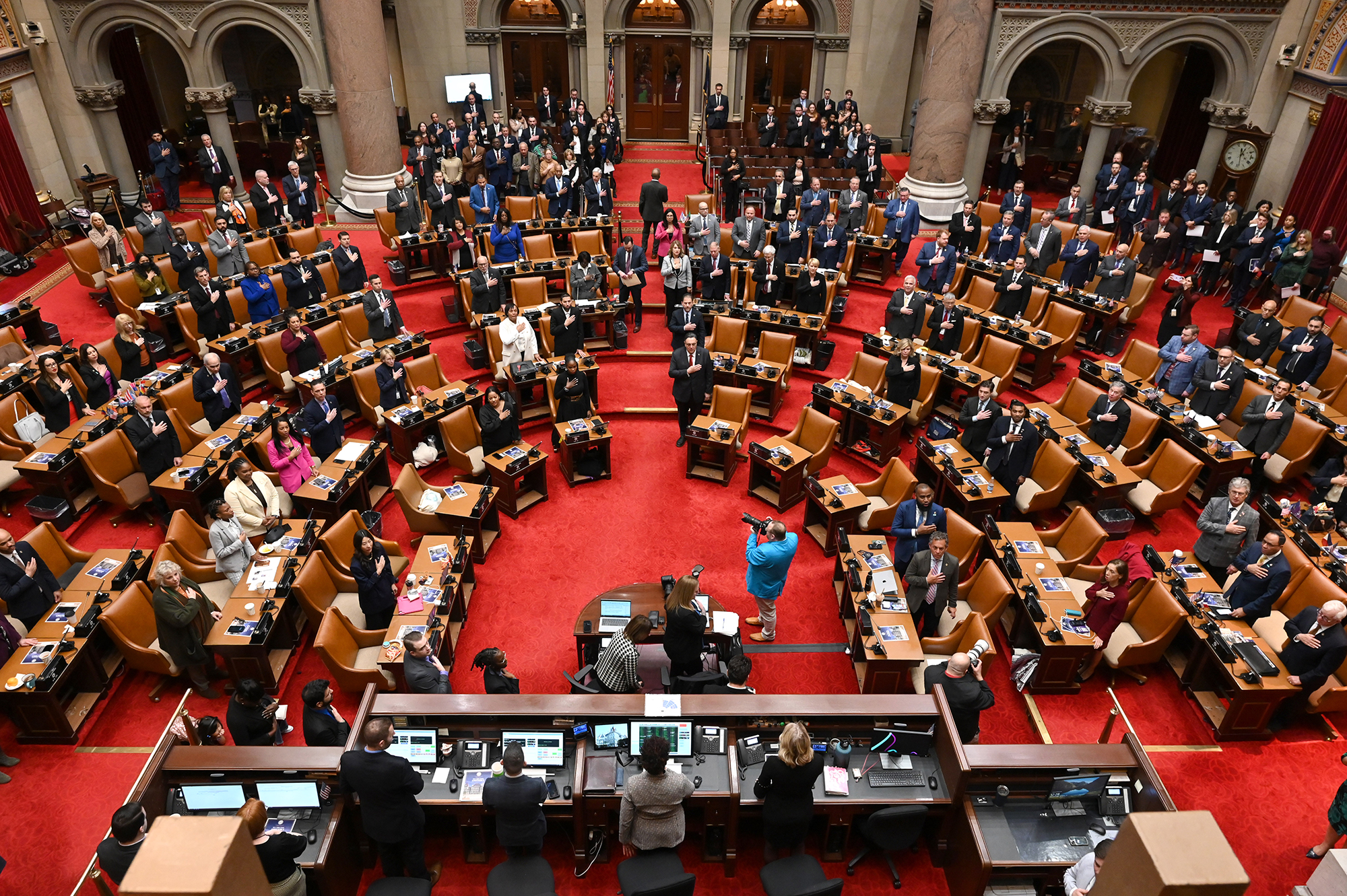 Assembly members stand for the Pledge of Allegiance in the Assembly Chamber in the New York State Capitol.
