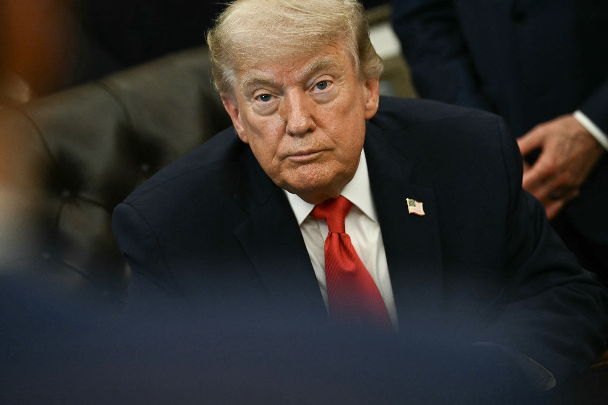 President Donald Trump sits in the Oval Office of the White House before signing a proclamation in June.