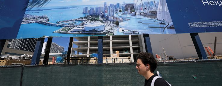 Pedestrians pass by a billboard featuring a condo building being built in downtown in Miami in August 2025.
