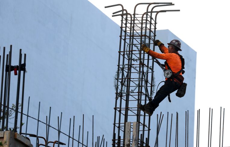 A construction worker helps build a support column using steel rebar in Miami.