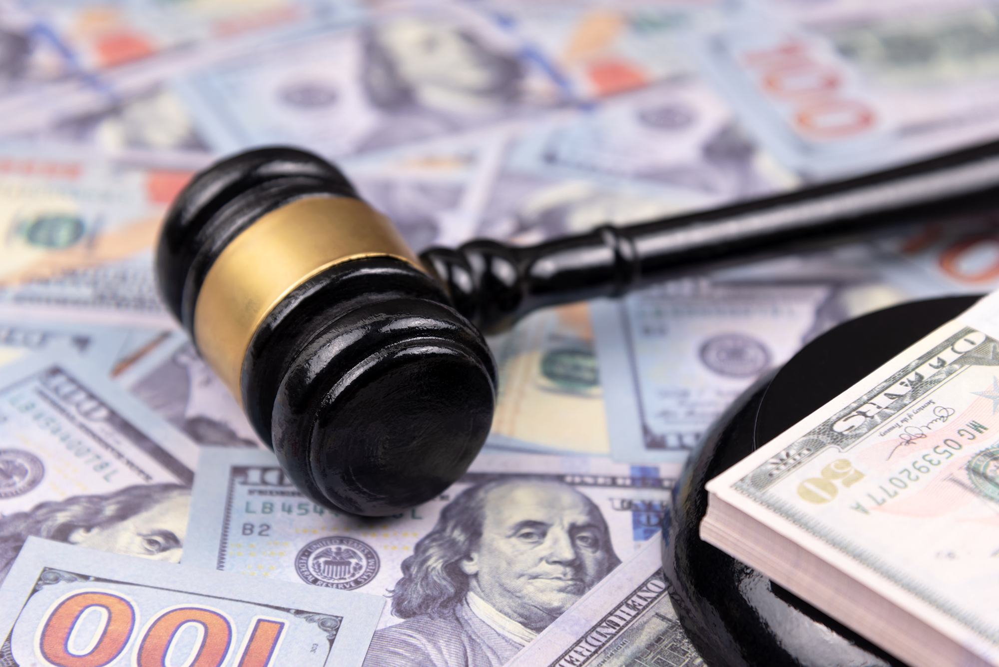 An illustration of a gavel on hundred dollar bills.