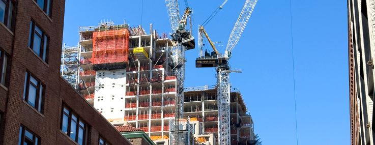 Construction cranes stand over a new residential building under construction.