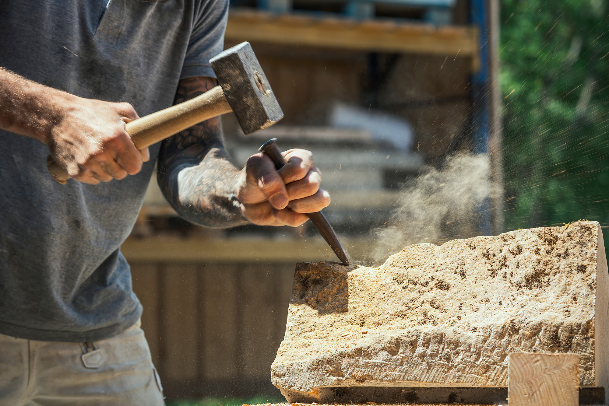A stonecutter hammering a piece of stone with a chisel.