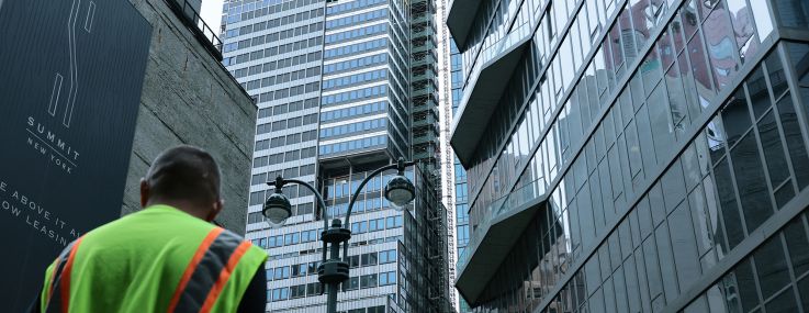 A construction worker stands near the former Pfizer headquarters building at 235 East 42nd Street after the building was evacuated when it was determined that it was at risk of collapse.
