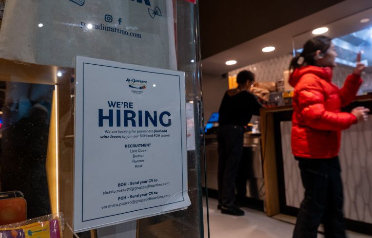 A restaurant displays a 'hiring' sign in its window in Manhattan.