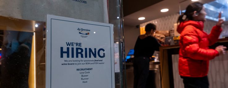 A restaurant displays a 'hiring' sign in its window in Manhattan.
