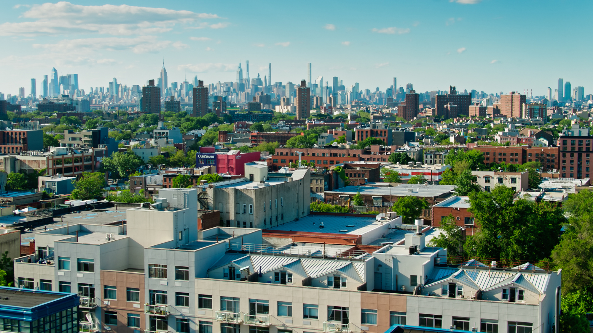 Aerial shot of New York City on a sunny afternoon in summer from over the Crown Heights neighborhood in Brooklyn and looking towards the Manhattan skyline.