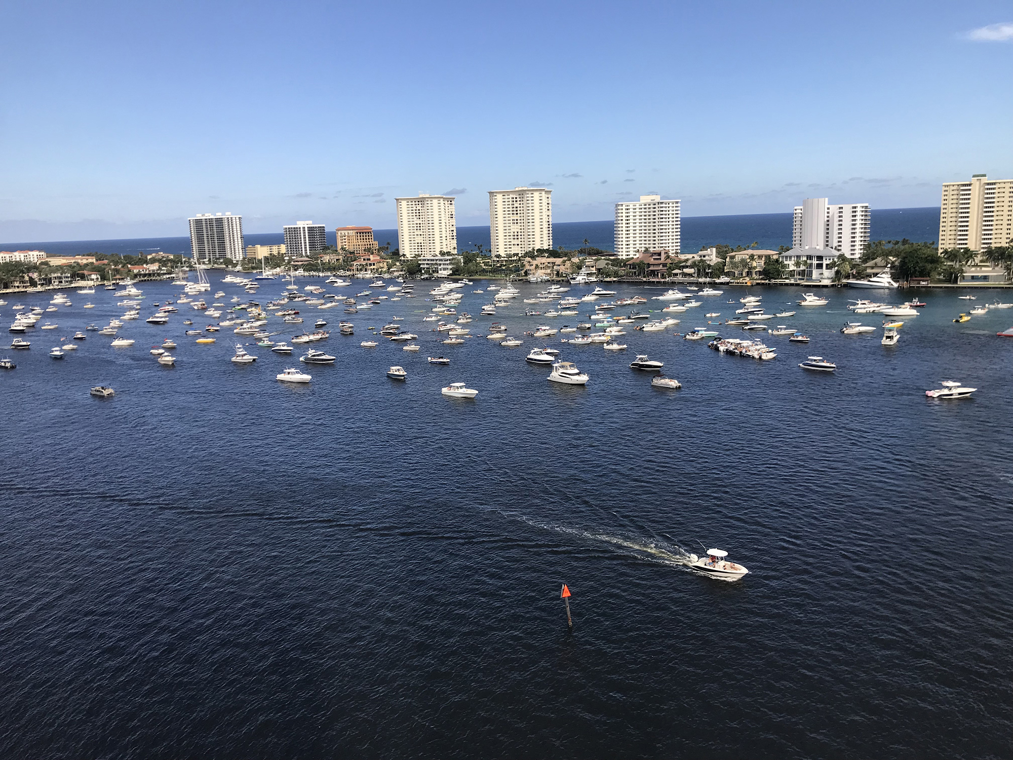 Hotel view of boats and yachts cruising in West Plam Beach, FL on a summer day. Hotels, condos and beach view in the horizon.