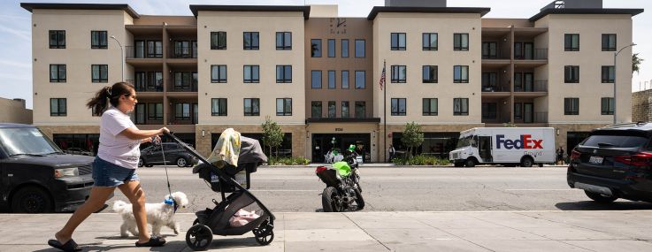 A woman passes by Vista Terrace, a 102-unit, affordable and supportive housing apartment complex on Van Nuys Boulevard in Los Angeles.
