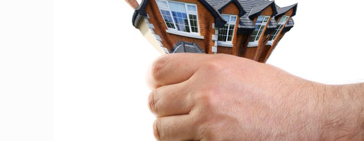 A photo illustration of a multifamily building getting squeezed by a hand.