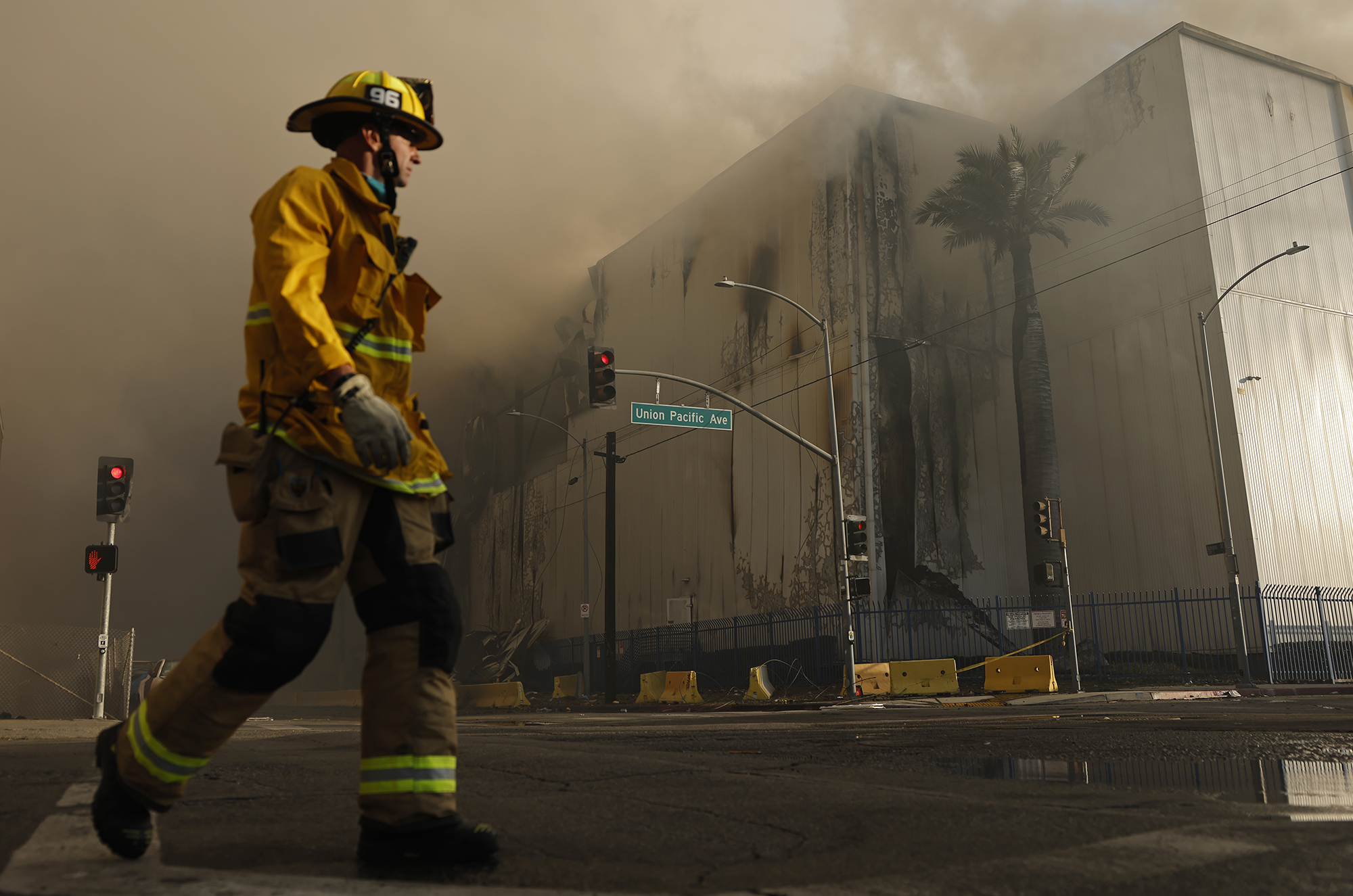 A firefighter walks down the street as a massive warehouse fire at a Lineage cold storage facility burns on June 20 in Los Angeles.