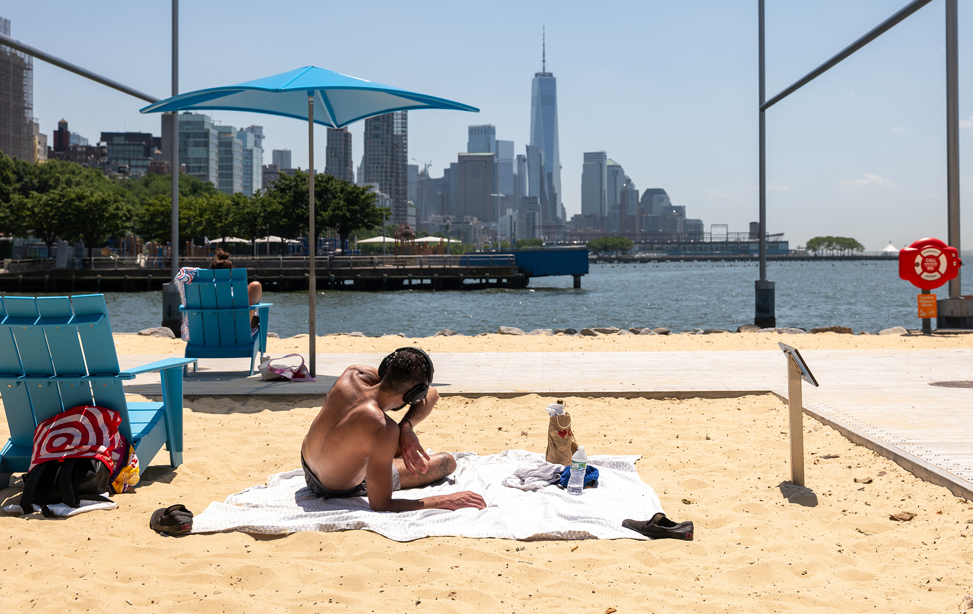 People relax at a man-made beach during a heat wave in Manhattan.