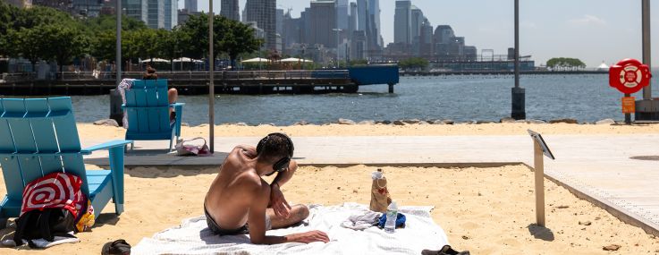 People relax at a man-made beach during a heat wave in Manhattan.