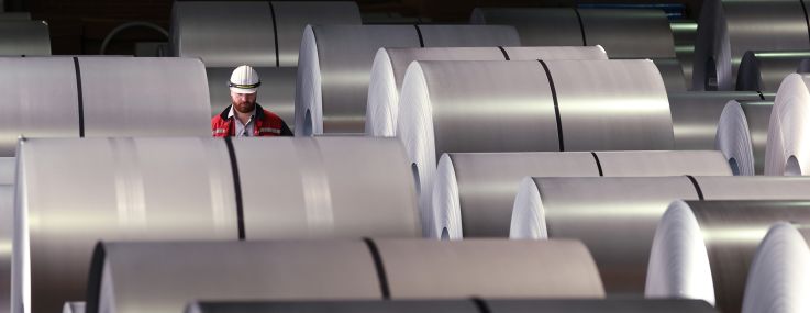 A worker walks among coils of finished steel at the Thyssenkrupp steel plant in Duisburg, Germany.