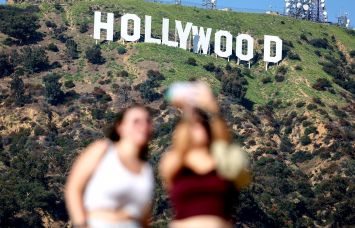 People pose for photos beneath the Hollywood sign in Los Angeles.