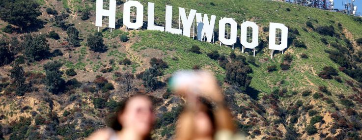 People pose for photos beneath the Hollywood sign in Los Angeles.