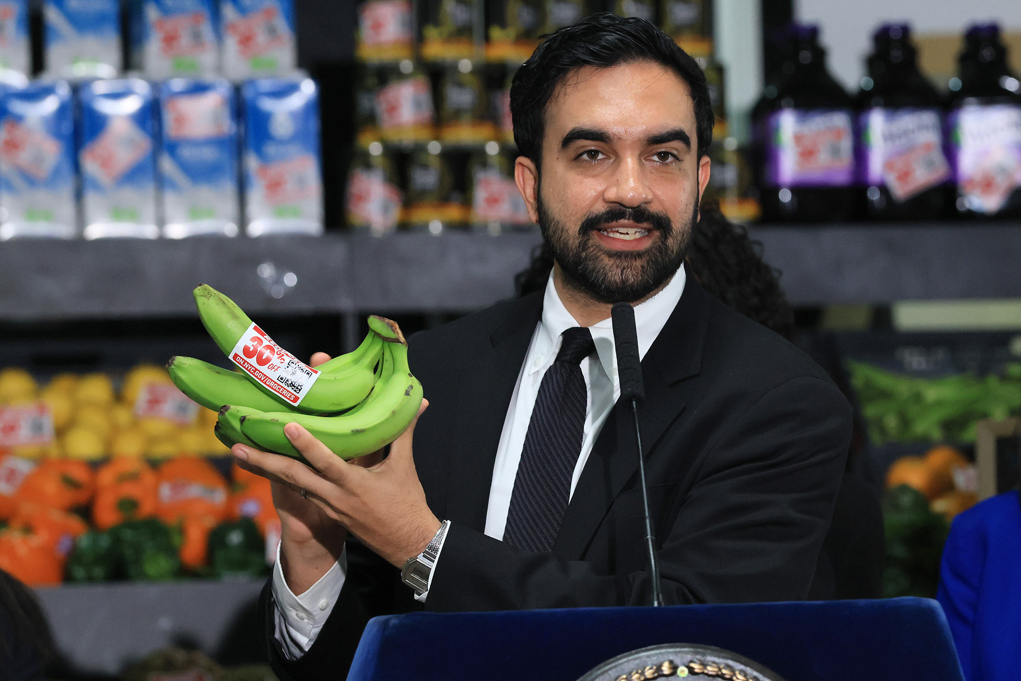 Mayor Zohran Mamdani holds up bananas as he announces five upcoming city-owned grocery stores will offer a 30 percent discount on produce, meat, bread and milk when they open.