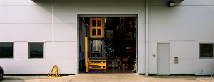 A forklift at the entrance to a warehouse.