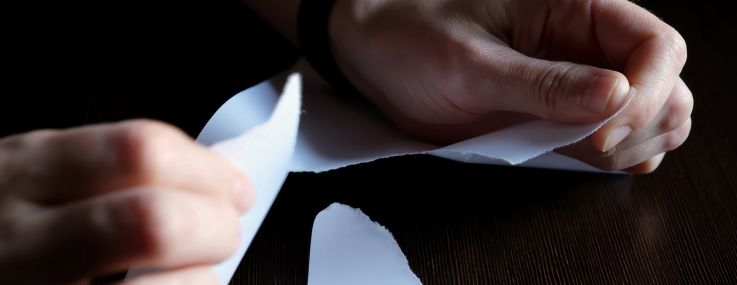 A pair of hands tearing up a piece of paper.