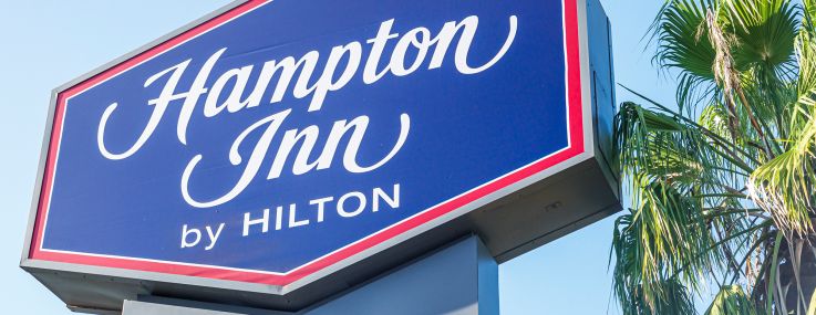 A Hampton Inn by Hilton sigh with a palm tree in the background.
