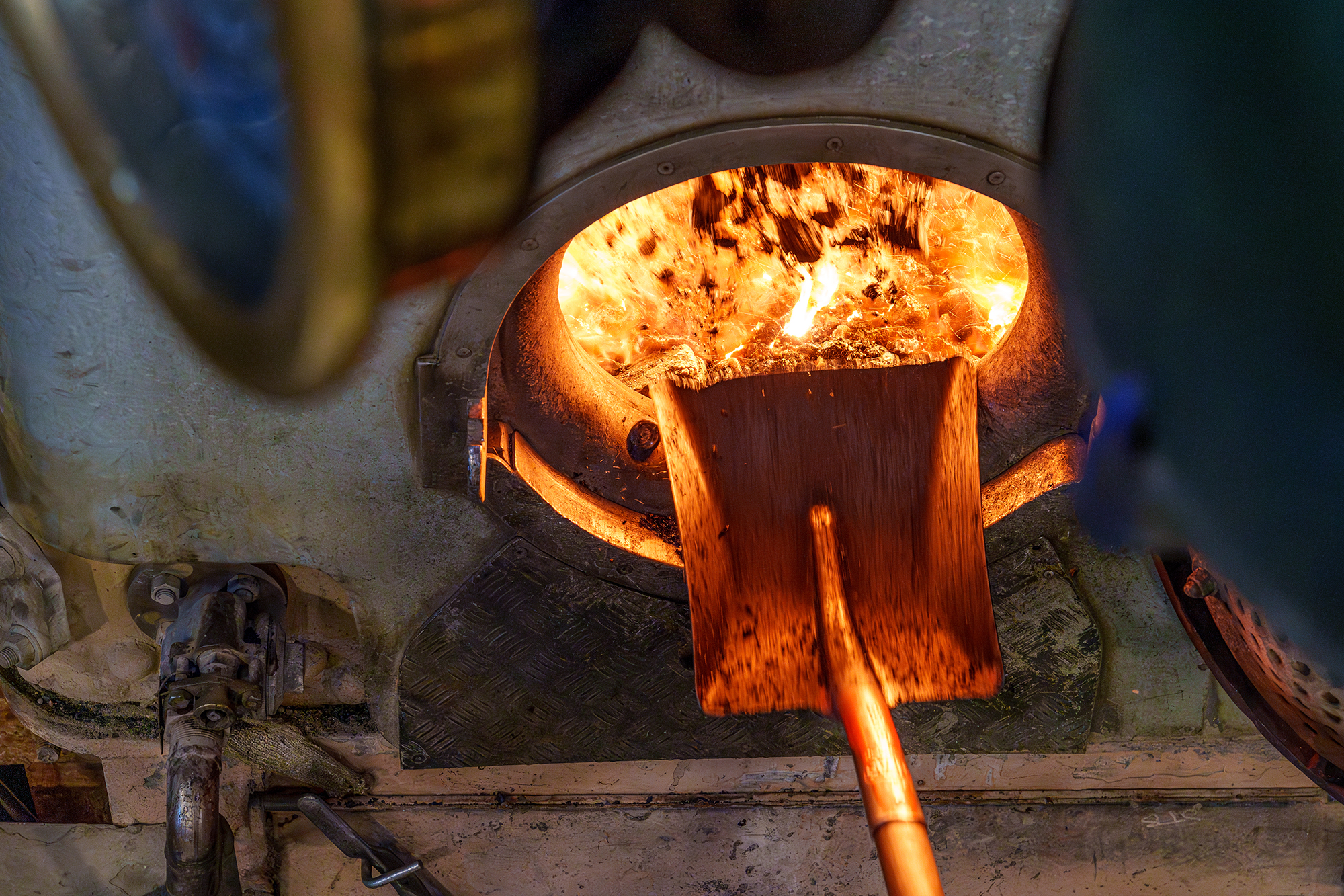Coal being shoveled into the firebox of an old steam ship.