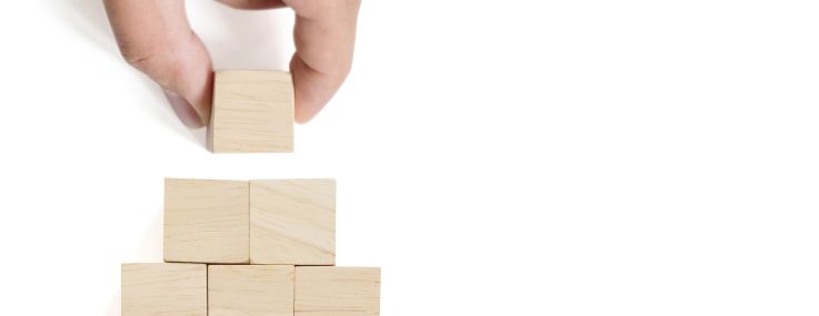 Hand arranging wood block stacking on top pyramid with white background. Business concept for growth success process